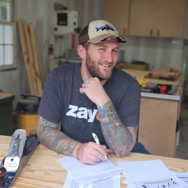 Trey at the workbench in his woodworking shop, reviewing project plans